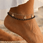 خلخال ذهبي مزين بحبات سوداء وتصميم أنيق يزين الكاحل