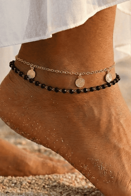 خلخال ذهبي مزين بحبات سوداء وتصميم أنيق يزين الكاحل