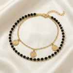 خلخال ذهبي مزين بحبات سوداء وتصميم أنيق يزين الكاحل