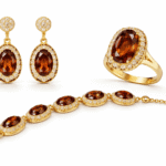 طقم مجوهرات فاخر يضم أقراطًا وخاتمًا وسوارًا بحجر بيضاوي عسلي محاط بكريستالات لامعة وإطار ذهبي أنيق.