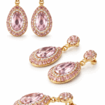 أقراط ذهبية أنيقة مرصعة بحجر وردي بيضاوي محاط بكريستالات لامعة بتصميم فاخر.